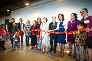 A photo of the official ribbon cutting ceremony for the PAO Arts Center with many of hte people involved holding up the ribbon to be cut.