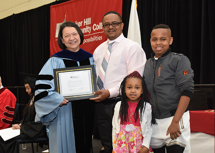 Student receiving his award with his family by his side