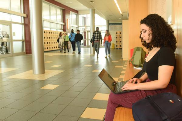 student studying with other students walking through the hallway