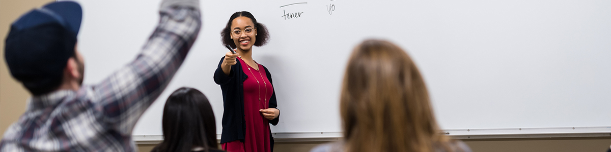 student at a whiteboard with other people raising their hands student at a whiteboard with other people raising their hands