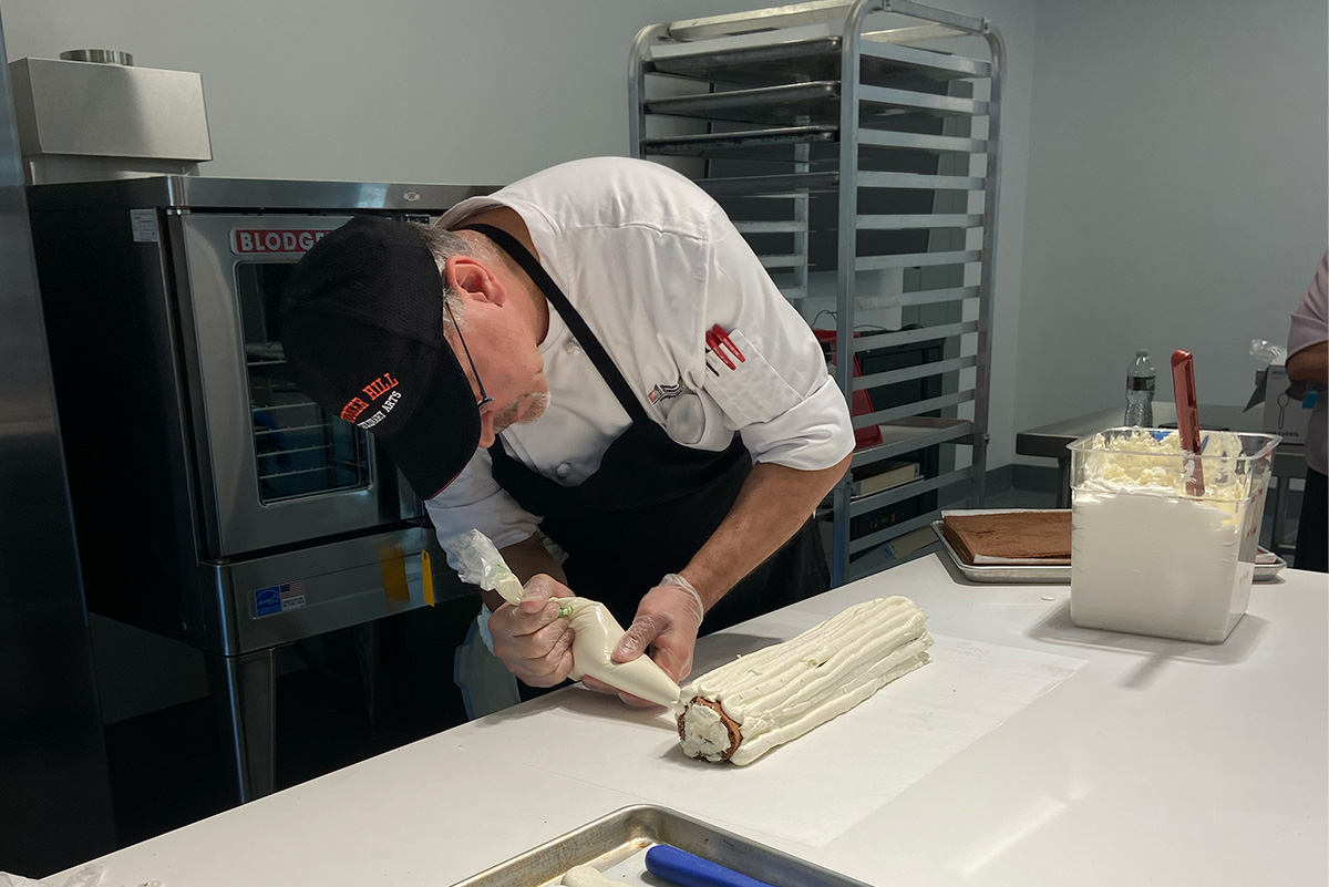 chef frosting a cake with a piping bag