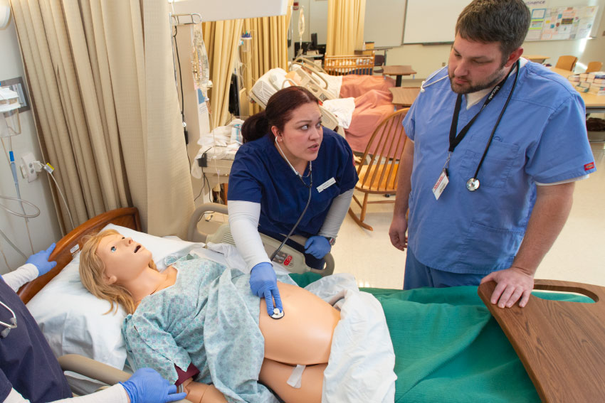 Two Nursing Students examining an adult Manikin