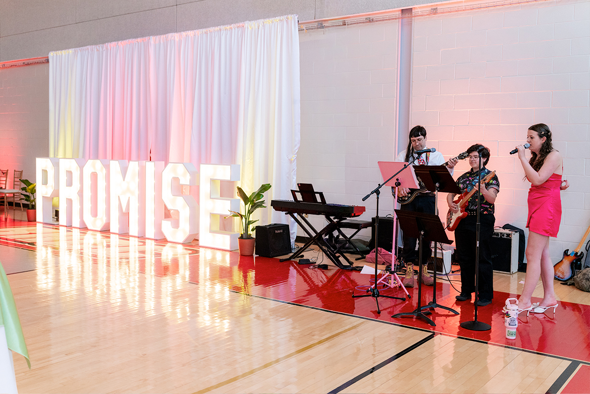 students performing in front of a sign that says promise