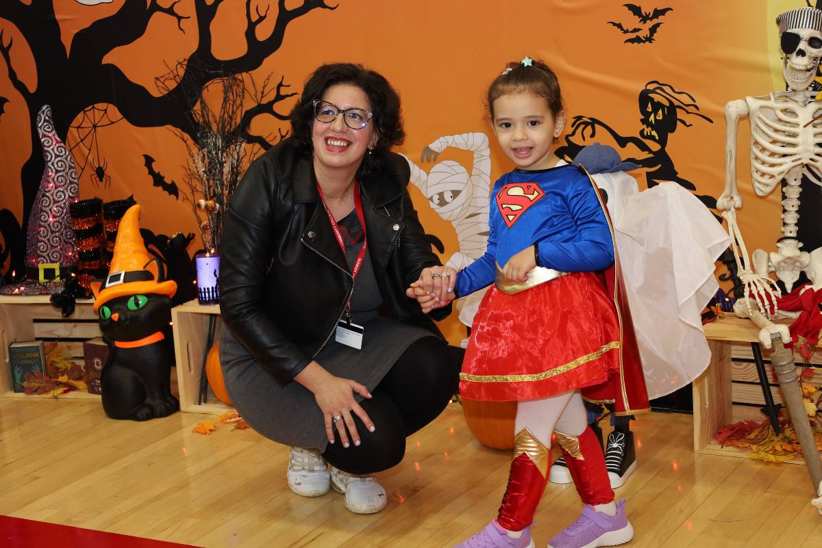 a child with superman costume and adult posing for pics